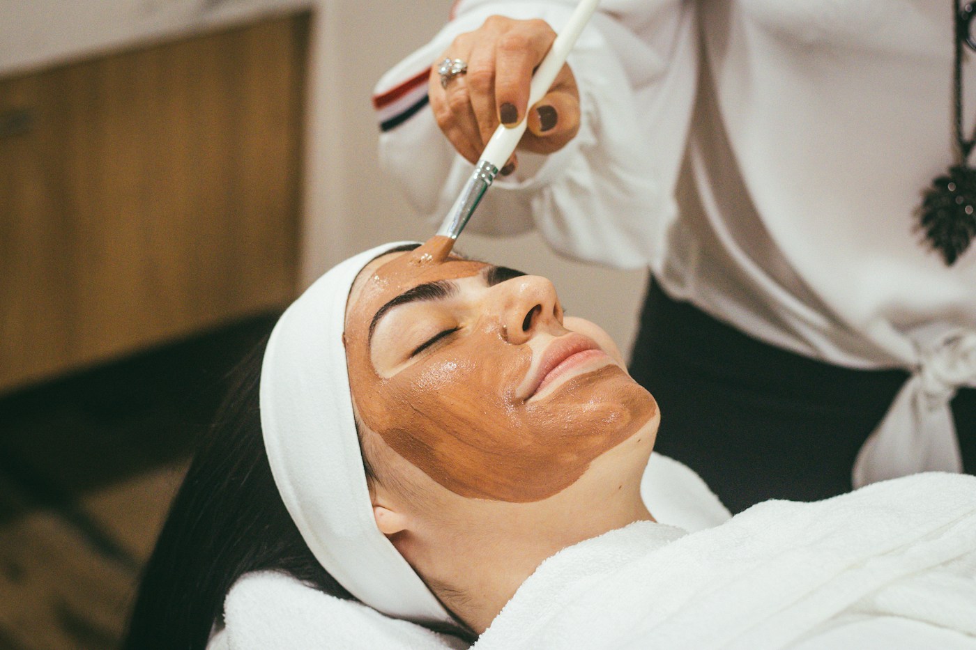 Provider carefully applying a facial treatment to a relaxed patient